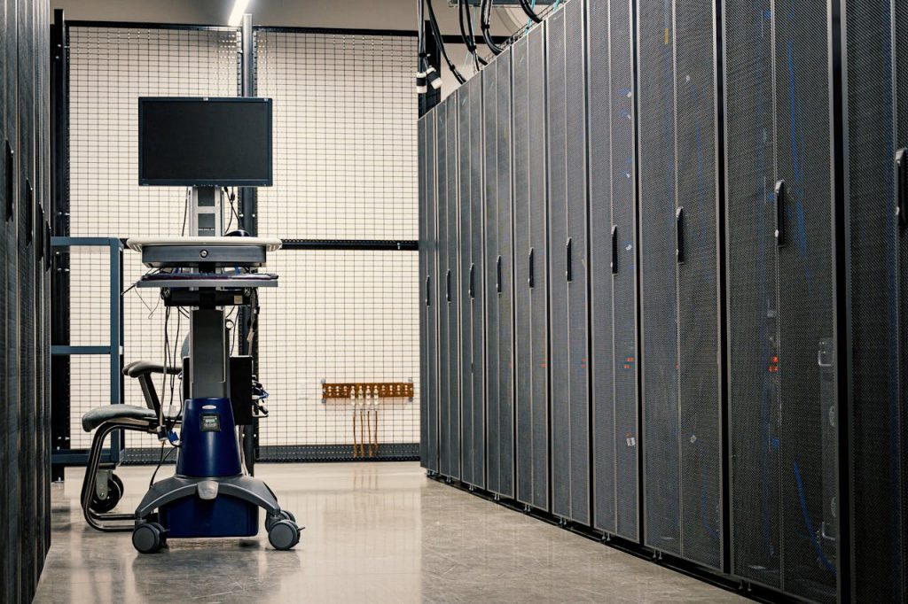 Contemporary computer on support between telecommunication racks and cabinets in modern data center